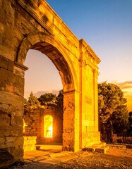 Fototapeta premium Golden sunset through ancient arches at a coastal ruins site near the sea
