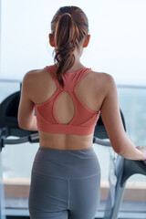 Woman stands at gym equipment, focusing on her fitness journey. She embodies wellness and self care through her exercise routine, promoting healthy lifestyle