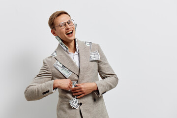 Confident smiling woman with short hair and glasses wearing a beige blazer with dollar bills pinned...