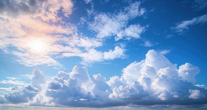 Bright blue sky filled with large fluffy white clouds illuminated by warm sunlight creating a serene and uplifting atmosphere