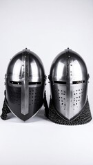 Two medieval helmets, one with chainmail, displayed against a white backdrop