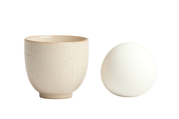 A modern ceramic bowl with a cracked texture next to a smooth white egg on a white background.