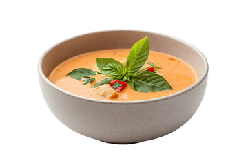 Delicious bowl of creamy soup garnished with fresh basil and red chili peppers.