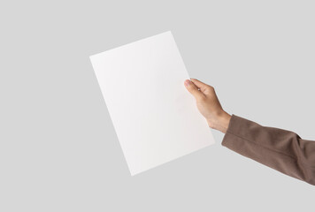 hand showing blank paper A4 flyer for mockup template logo branding on grey background.