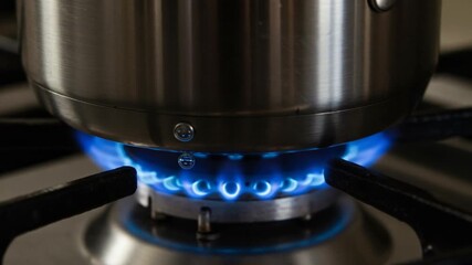 Cooking pot on gas stove with blue flame igniting