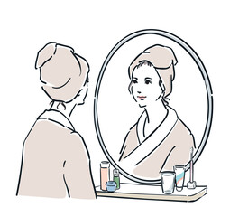 鏡の前に立つバスローブ姿の女性