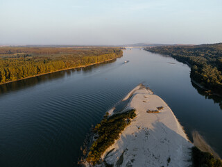 Aerial view of a serene river island at sunset, surrounded by lush forest. g.