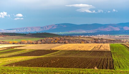 Obraz premium Autumnal farmland landscape with rolling hills and mountains in the distance