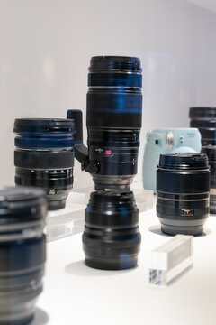 A group of camera lenses from various brands including Canon and Sony, displayed together in a store. The collection demonstrates diversity in focal lengths and advanced optical design for professiona