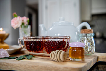 Close up of pink tea cups and honey with honey wand and roses in a crystal cup. 