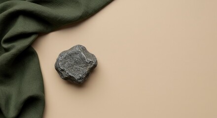 Serene Still Life: Textured Green Fabric, Rough Stone on Beige Backdrop