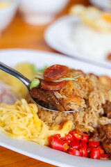 Aromatic Culinary Creation: A close-up shot of a vibrant Thai dish on a pristine white plate, featuring a spoonful of aromatic rice, flavorful condiments and enticing presentation.