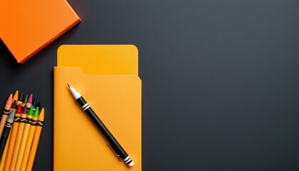 Bright yellow notebook with black pen and colorful pencils on dark gray background ideal for stationery and office supplies concepts