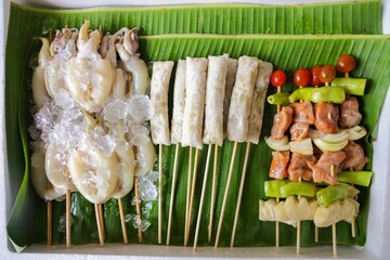 Skewered Delights: A vibrant display of raw, ready-to-grill seafood and vegetables, artfully...