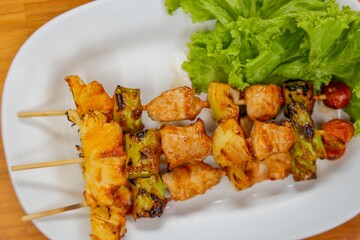 Grilled Skewers on Plate: A delicious composition of grilled skewers presented on a clean, white plate, garnished with vibrant lettuce. Each skewer boasts a variety of grilled elements.