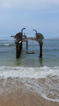 Beach Swing Under Swan Statue at Angso Duo Island Landmark, Indonesia