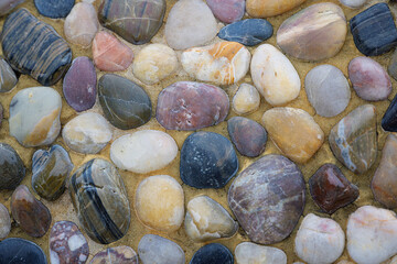 2023-12-31 SEVERAL MULTI COLORED RIVER ROCKS SET IN PLASTER AS A BACKGROUND WITH NICE COLORING