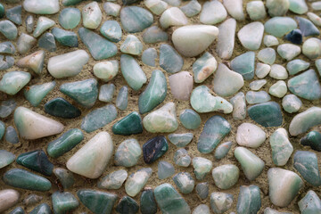 2023-12-31 VARIOUS SMOOTH COLORFUL ROCKS SET IN CONCRETE AS A BACKGROUND