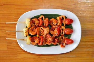 Grilled Skewers Delight: A top-down shot reveals a trio of appetizing skewers arranged artfully on a pristine white plate, ready to be devoured