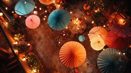 Overhead shot of colorful paper umbrella decorations hanging from a ceiling with string lights creating a festive atmosphere