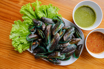 Fresh Seafood Platter: An appetizing seafood platter with fresh green mussels arranged artfully, complemented by vibrant dipping sauces and crisp green lettuce