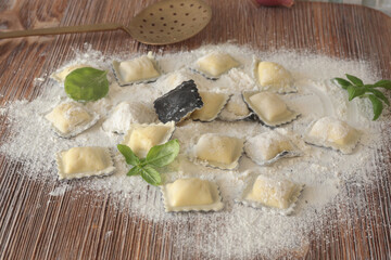 Homemade ravioli with basil leaves on wooden board. Healthy food and organic products.