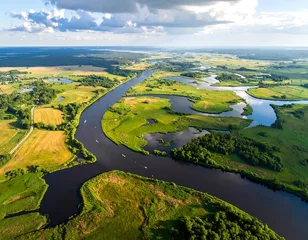 Tableau sur plexiglas Prairie, marais A serene river winds through a landscape of meadows, fields, and forests, showcasing a peaceful rural scene from a high-altitude perspective.  © Gardah