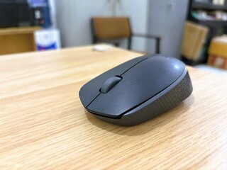 A wireless mouse placed on a wooden table.