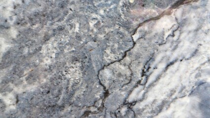 A close-up shot reveals a detailed, textured surface with a blend of white, gray, and dark veins, resembling natural stone or marble.