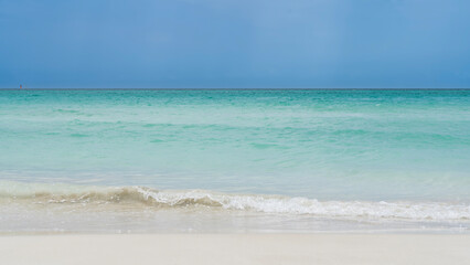 Beautiful serene minimalistic seascape. The waves of the aquamarine ocean are foaming on the white sandy beach. The horizon above the water. Clear blue sky. Cuba. Varadero.