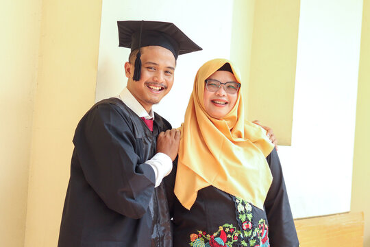 Portrait of Graduate Asian man Holding Diploma with his mother in Hallway