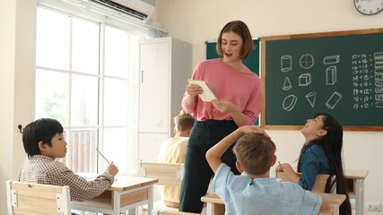 Smart asian student raised hand and asking teacher about math question while teacher walking and checking homework at elementary classroom. Teacher answering question while pick up notebook. Pedagogy. - Powered by Adobe