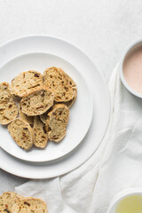 overhead view of slices of savory biscotti with dip, top view of thinly sliced bread chips with sauce, top view of crostini bread slices on marble countertop