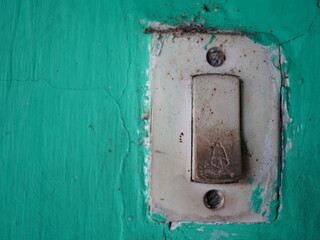 Grungy old light switch on distressed teal wall showing neglect and wear