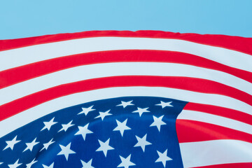 The US flag is waving in the wind.Close-up of the American flag hanging against a clear blue sky.