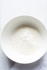 overhead view of All purpose flour in a bowl, top view of baking flour in a ceramic bowl