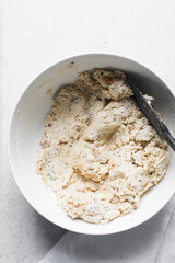 overhead view of savory biscotti dough in a bowl, top view of savory cookie dough in a mixing bowl