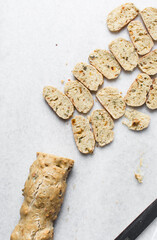 overhead view of slices of savory biscotti, top view of thinly sliced bread for making bread chips, top view of crostini bread slices on marble countertop