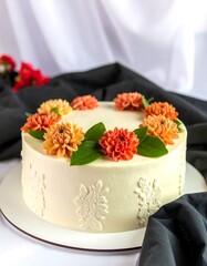 Round cake with orange & peach flowers, cream frosting, and white decorations