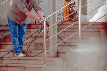 A woman cleans the porch steps with a contactless washer autumn day