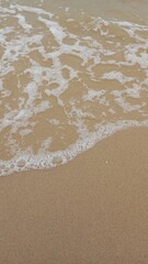 Foamy white ocean waves on the sandy beach