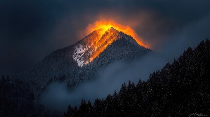 A snow-capped mountain peak bathed in a fiery sunset glow.