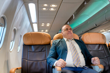 The fat businessman sitting on airplane seat to travel by airline service.