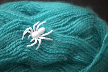Close-up of a green yarn ball with a white plastic spider on top. Concept of life’s web, fate,...
