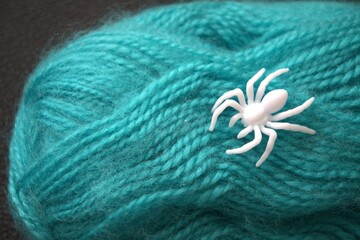 Close-up of a green yarn ball with a white plastic spider on top. Concept of life’s web, fate, and predestination.