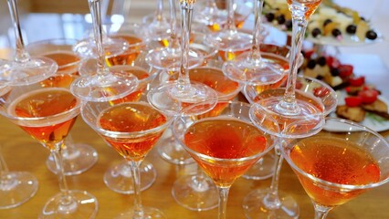 Champagne glasses stacked in pyramid shape, filled with sparkling orange drink, highlighting festive celebration atmosphere with elegant visual arrangement