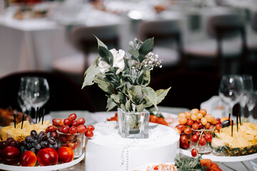 Elegant fruit display and floral arrangement at a festive gathering in a modern venue