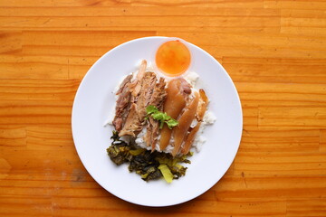 Succulent Pork and Rice Delight: A tempting overhead shot of a culinary masterpiece, featuring tender pork atop a bed of fluffy rice, alongside an enticing garnish on a pristine white plate.