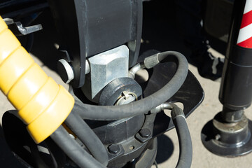 Close-up view of mechanical parts and hydraulic hoses on heavy machinery in the construction site during bright daylight