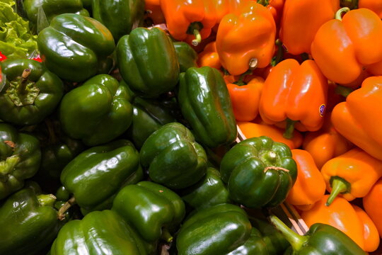 Colorful assortment of fresh green and orange bell peppers displayed at a local market, inviting shoppers to select their favorites